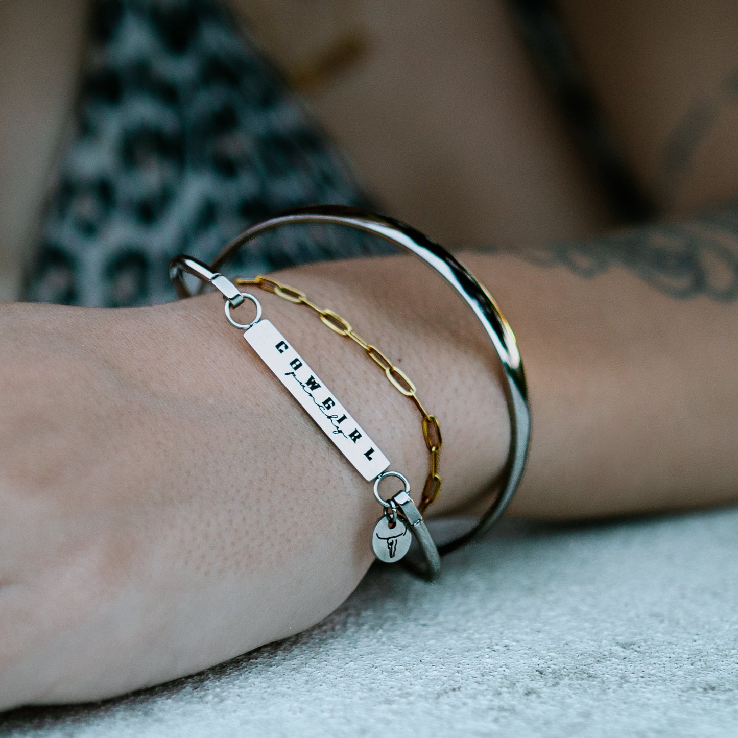 Close-up of a hand wearing multiple bracelets and rings on a blurred background